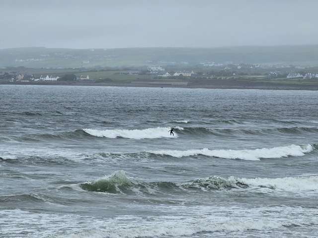 Junior surfer riding a shoulder high wave in the middle of the beach